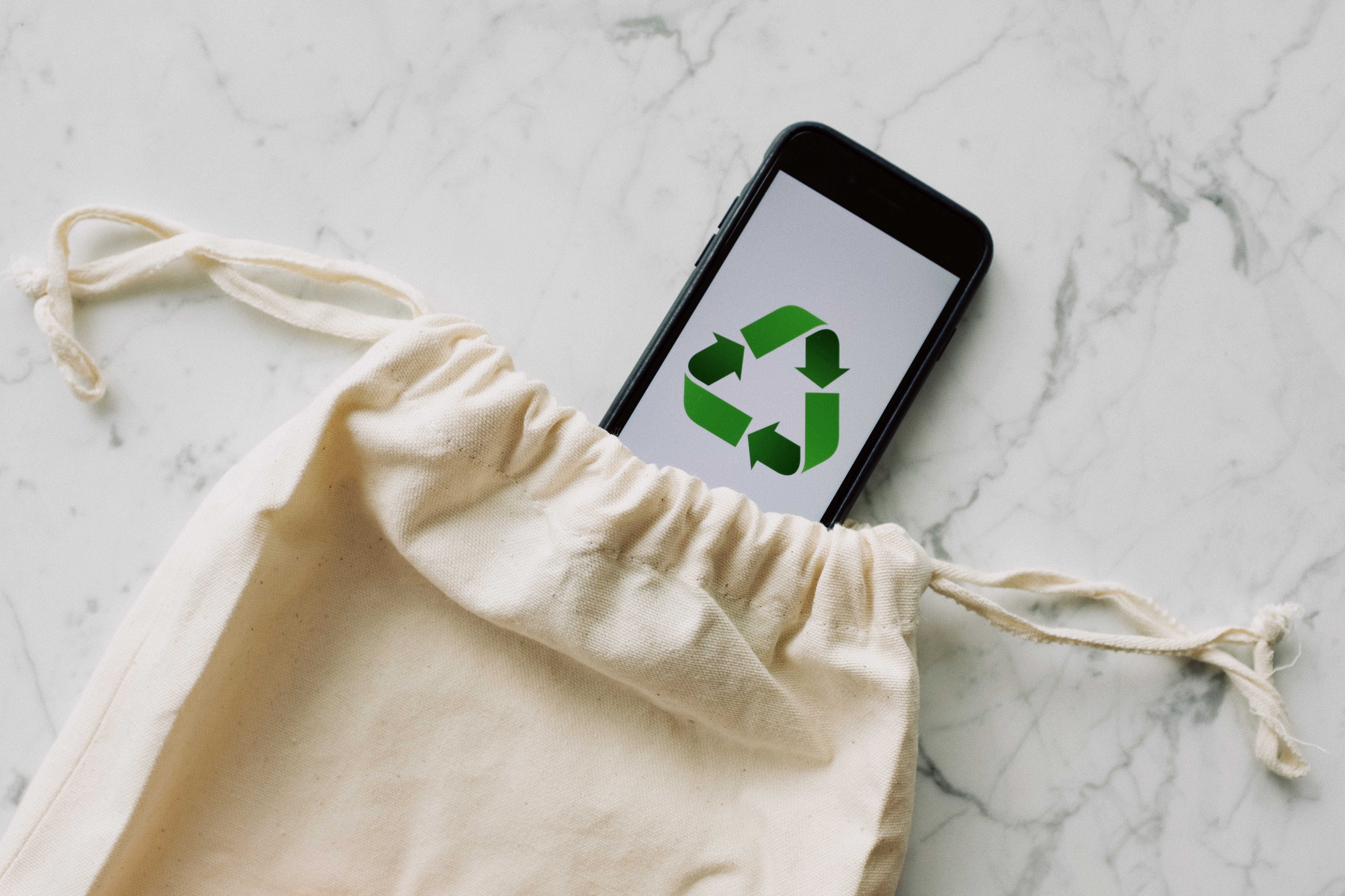 Image with a cellphone with the recycling logo and a tote bag